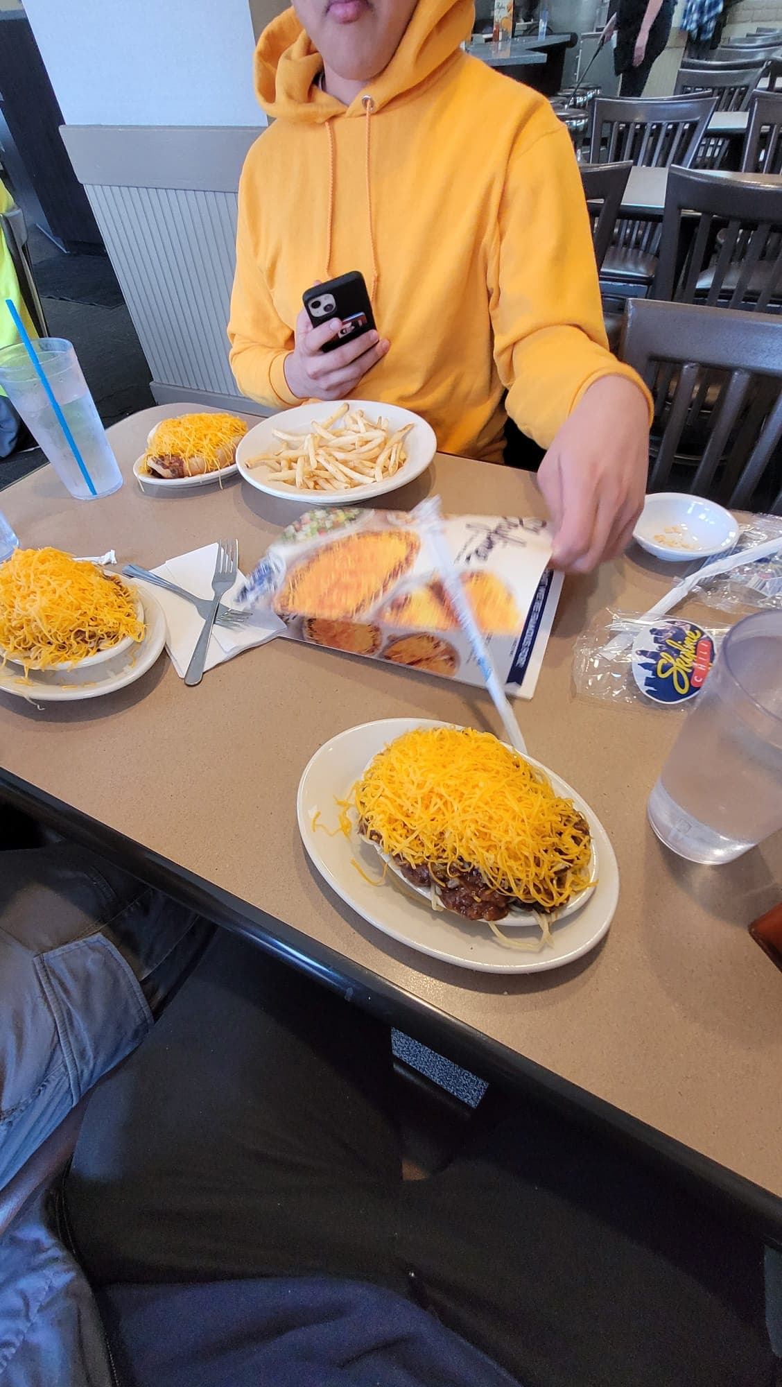 Plates of Cincinnati Skyline Chili coneys and cheese on a restaurant table