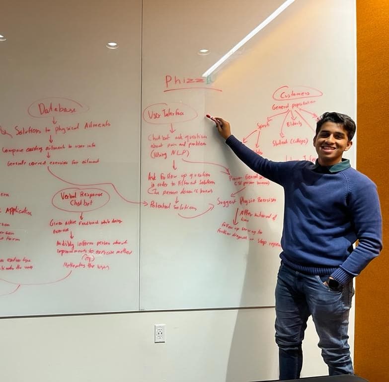 Aniruddhan at a whiteboard mapping out the early PhizzIO concept, with branches for the database, user interface, NLP chatbot, and target customers