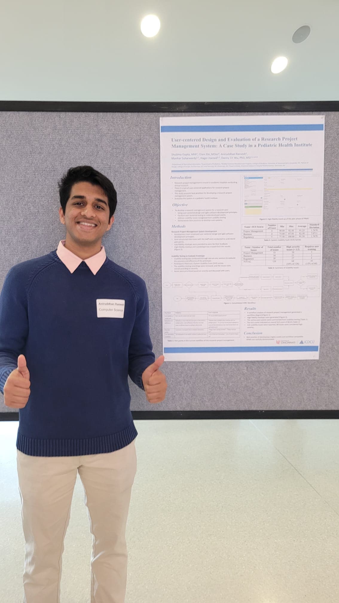 Aniruddhan giving a thumbs-up beside his HIRConnect research poster at the Undergraduate Scholarly Showcase